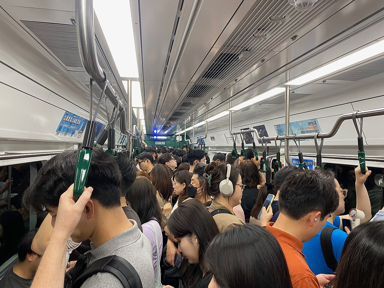 Crowded Seoul subway car at peak hour with passengers standing and holding overhead straps photo_0